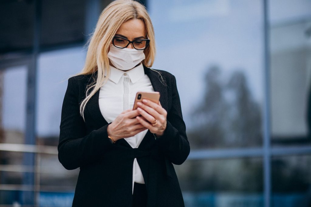 Mulher com máscara e smartphone